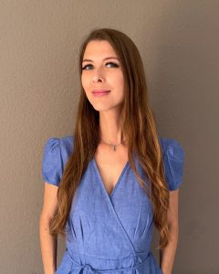 Kirjailija Tiina Pasanen katsoo seinän edessä suoraan kameraan