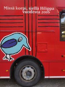 Kuvassa on kirjastoauton kylkeä. Kyljessä lukee: Missä korpi, siellä Hilippa vuodesta 2016. Kyljessä on lisäksi piirroskuva linnusta.